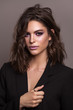 Portrait of young beautiful brunette model with violet professional make up, trendy wavy hairdo and perfect skin.