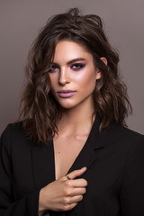 portrait of young beautiful brunette model with violet professional make up, trendy wavy hairdo and 