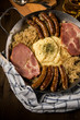 Sauerkraut Pfanne mit Nürnberger Rostbratwürste, Kassler Nacken,  Kartoffelpüree Senf und Bier auf Holz Tisch