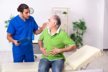 Old man visiting young male doctor gastroenterologist