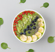 Healthy breakfast smoothie bowl topped with blueberry, kiwi, banana, spinach, Chia seeds and Goji berries. Detox concept. Green smoothie bowl on grey background. Top view.