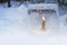 Winter Lantern Made Of Ice, Burning Candle Inside, In Snowfall.
