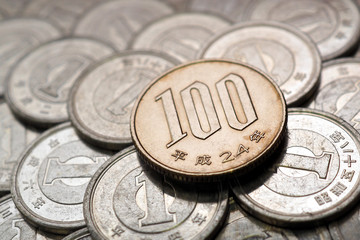 Wall Mural - A field of Japanese coins in 1 yen, on it lies a coin of 100 yen. News about the economy, finances and interest rate of the central bank of Japan. Deposits and loans. High contrast shot. Macro