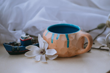 beautiful cup with tea with blue decor in the morning with a flower and a decorative boat