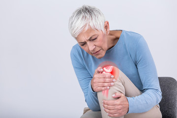 Senior woman holding the knee with pain. Old age, health problem and people concept - senior woman suffering from pain in leg at home. Elderly woman suffering from pain in knee at home