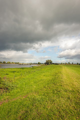 Wall Mural - Dark clouds above a wide Dutch river