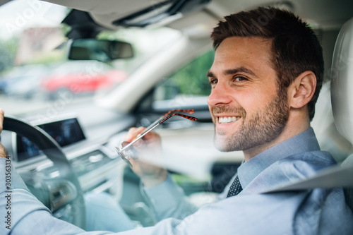 Fotografía Young businessman with shirt sitting in car. Shot through glass.