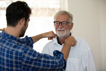 Hipster man taking care about his elderly father in house.