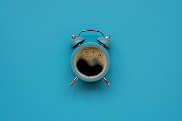 alarm clock as coffee cup on blue background. top view. flat lay. good morning concept