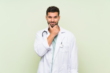 Wall Mural - Young doctor man over isolated green wall laughing