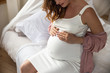 Pretty smiling expectant mother in bedroom at home