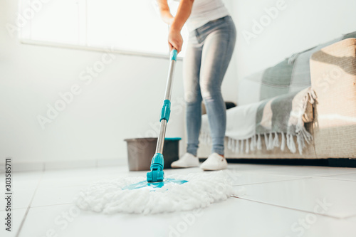 Fotografía Cropped image of young woman in using a mop while cleaning floor in the house