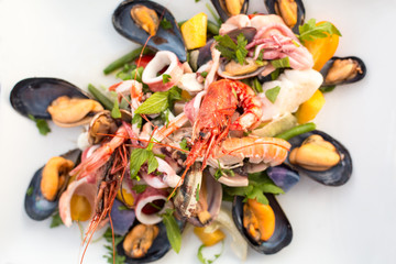 Canvas Print - Mixed seafood salad (shrimps, mussels, squids) on the table, located on the beach. Ischia, Italy.