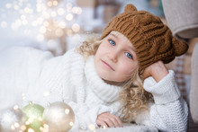 Girl In Knitted Hat Near Christmas Tree Makes A Wish For New Year.