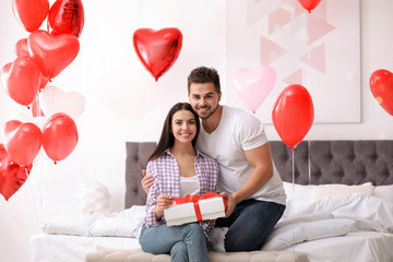 Sticker - Happy young couple in bedroom decorated with heart shaped balloons. Valentine's day celebration