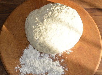 Homemade food. On the board lies a freshly kneaded dough made from wheat flour for making dumplings.