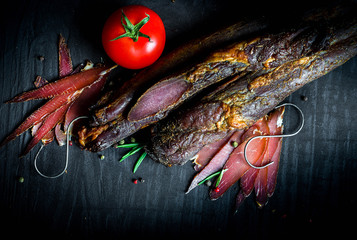 Wall Mural - A set of different types of raw smoked meat. Jamon Lomo, сoppa and fillet on a black background.