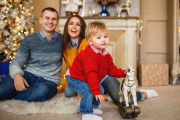 little girl playing with a toy. Her parents at background smiling and look at her