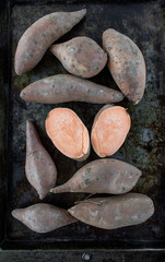 raw and whole sweet potato yams on baking tray flat lay