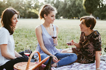 Mother and two daughters make picnic in a park at sunset during summer