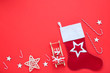 Red stocking with christmas ornaments and wooden sleigh on red background