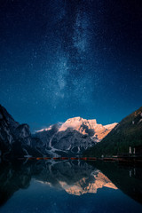 beautiful first light on a mountain top against stars and milky way in lago di praies, dolomites, it
