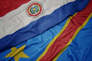 waving colorful flag of democratic republic of the congo and national flag of paraguay.