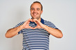 © Krakenimages.com - Young man wearing casual striped polo standing over isolated white background smiling in love doing heart symbol shape with hands. Romantic concept.
