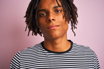 Wall Mural - Afro american man with dreadlocks wearing navy striped t-shirt over isolated pink background with a confident expression on smart face thinking serious