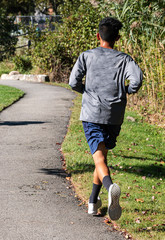 Sweaty runner in long sleeved shirt on a tar path in a park