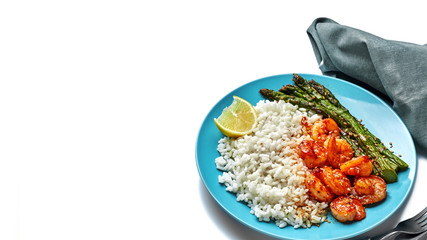 Wall Mural - Grilled shrimps and asparagus with rice and sesame on a blue table. Seafood meal dinner isolated on white background.