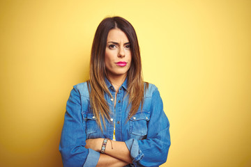 Canvas Print - Young beautiful woman standing over yellow isolated background skeptic and nervous, disapproving expression on face with crossed arms. Negative person.