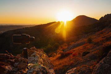 Wall Mural - Monopod stabilizer for a mobile phone in the mountains at sunset