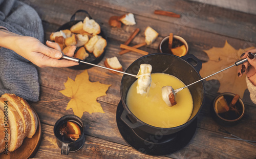 Fotografía Top view friends cooking Swiss fondue assorted cheeses dinner on fire, hands hol