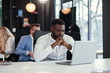 © gorynvd - Afro american young male office manager works with different reports with charts and table laptop at his workplace in the meeting room.