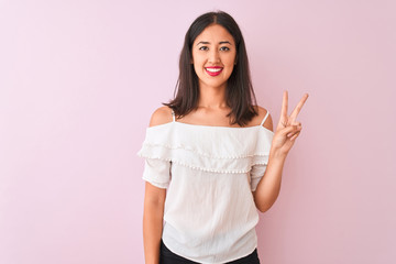 Beautiful chinese woman wearing white t-shirt standing over isolated pink background showing and pointing up with fingers number two while smiling confident and happy.