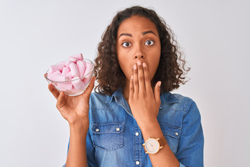 Canvas Print - Young brazilian woman holding bowl with marshmallows over isolated white background cover mouth with hand shocked with shame for mistake, expression of fear, scared in silence, secret concept