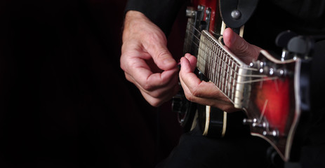 Wall Mural - Guitarist hands and guitar on a black background close up. playing electric guitar. copy spaces. 