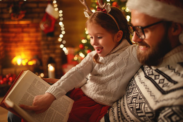 Wall Mural - christmas eve. family father and child reading magic book at home .