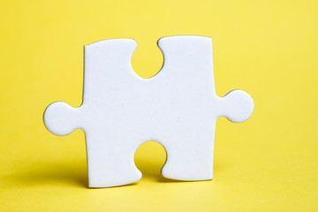 A piece of white puzzle on a yellow background. The concept of the necessary details for the task.