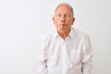 Poster - Senior grey-haired man wearing elegant shirt standing over isolated white background making fish face with lips, crazy and comical gesture. Funny expression.