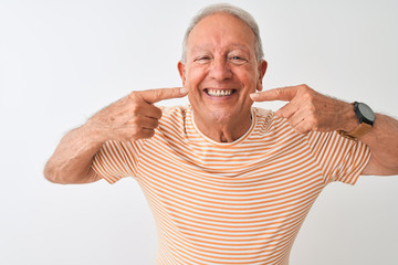 Poster - Senior grey-haired man wearing striped t-shirt standing over isolated white background smiling cheerful showing and pointing with fingers teeth and mouth. Dental health concept.