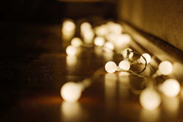 Wall Mural - Close up view of decorative wire led small warm white light bulbs lay on a floor at corner of dark and dim room. Romantic and decoration lightbulb.