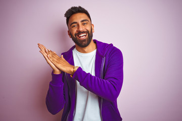 Sticker - Young indian man wearing purple sweatshirt standing over isolated pink background clapping and applauding happy and joyful, smiling proud hands together