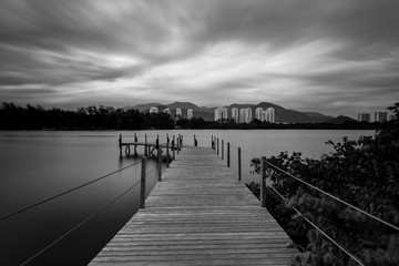  Long exposure of pier in calm lake, with nature all around, water is silky smooth, black and white