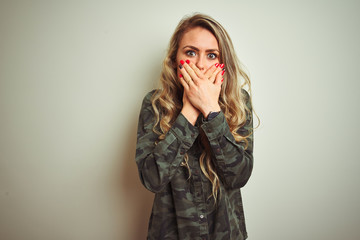 Wall Mural - Young beautiful woman wearing military camouflage shirt over white isolated background shocked covering mouth with hands for mistake. Secret concept.