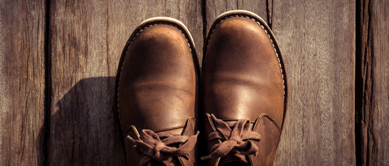 Wall Mural - Brown stylish boots on wood background,  retro color