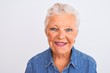 Senior grey-haired woman wearing casual denim shirt standing over isolated white background with a happy face standing and smiling with a confident smile showing teeth