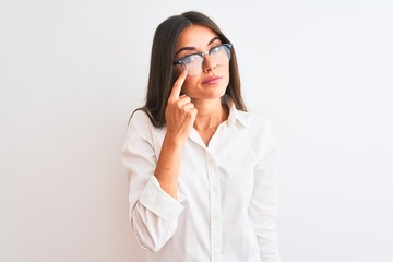 Wall Mural - Young beautiful businesswoman wearing glasses standing over isolated white background Pointing to the eye watching you gesture, suspicious expression