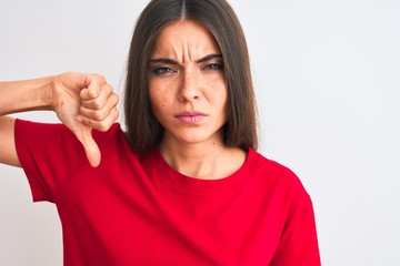 Wall Mural - Young beautiful woman wearing red casual t-shirt standing over isolated white background with angry face, negative sign showing dislike with thumbs down, rejection concept